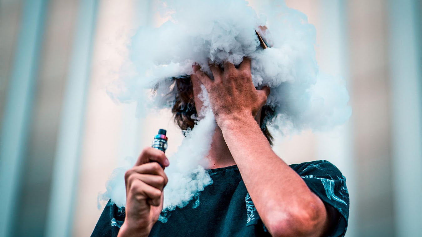 man blowing a large vape cloud