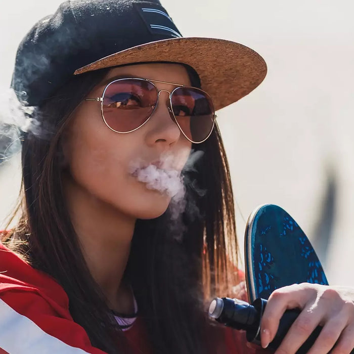Woman with snapback on ghost vaping