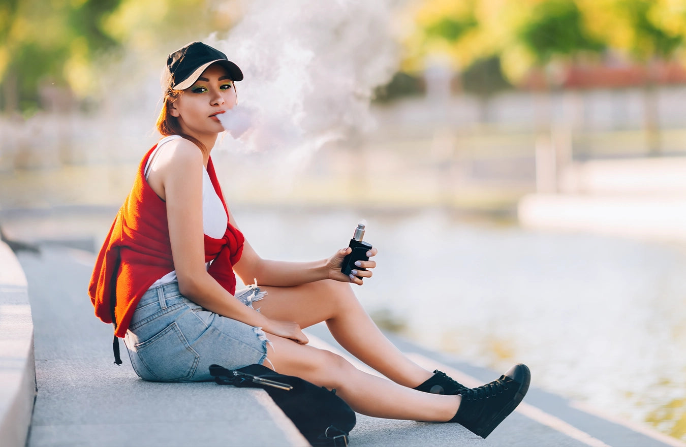 Woman sitting on concrete stairs vaping