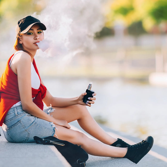 Woman sitting on concrete stairs vaping