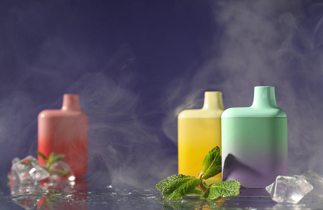 3 disposable vapes sitting on table with smoke on screen