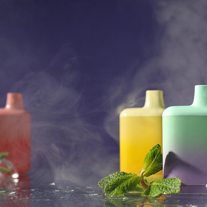 3 disposable vapes sitting on table with smoke on screen