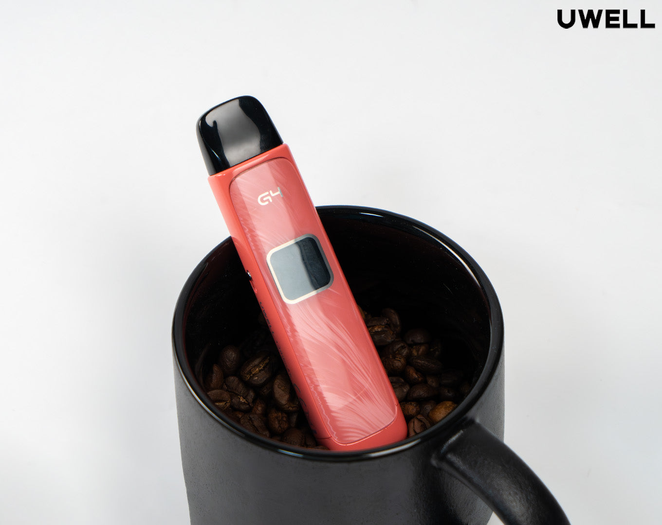 Red UWell Caliburn G4 sitting in a black coffee mug on top of coffee beans 