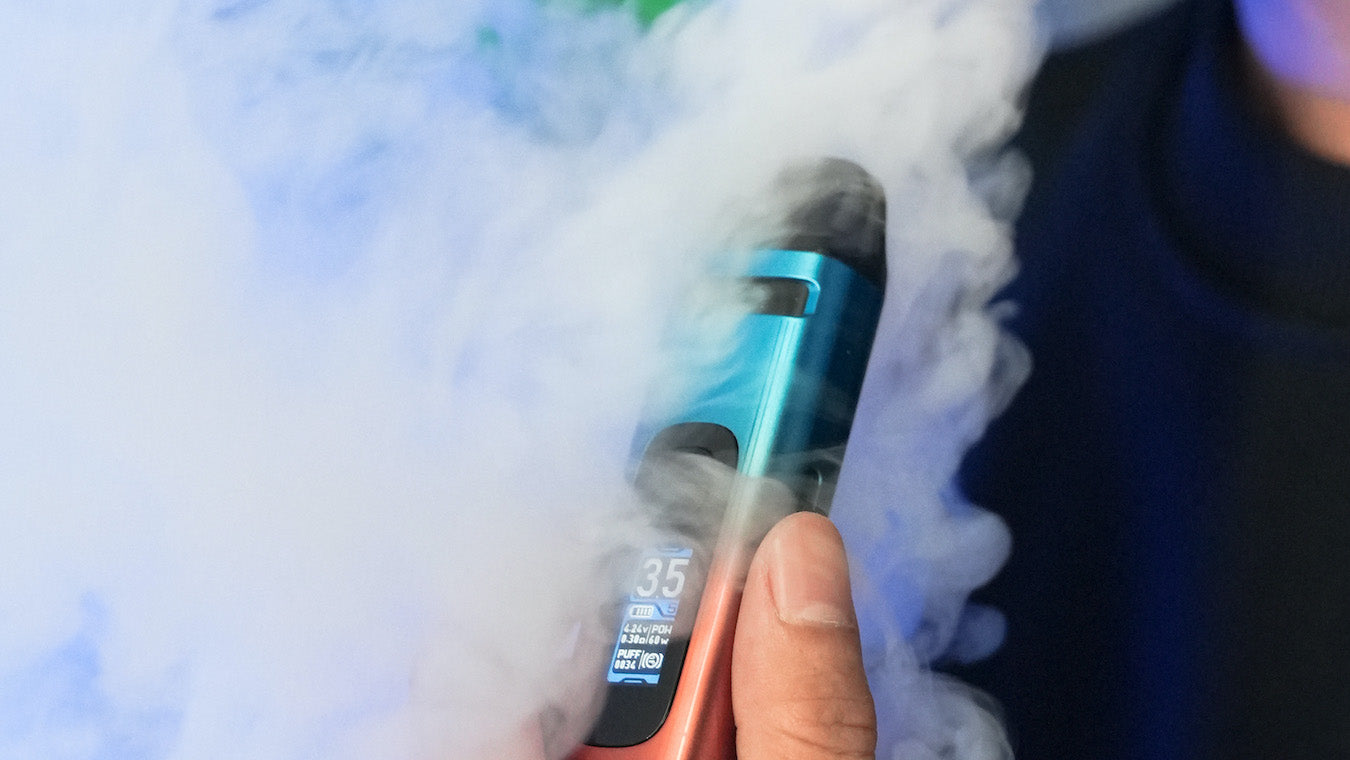 Man holding UWell Crown X device with billowing vapour surrounding